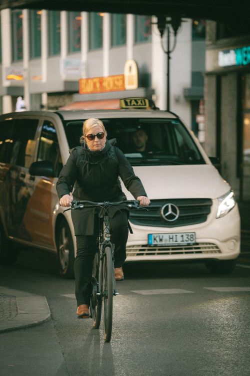 Free A cyclist rides through the busy streets of Berlin, Germany, in front of a taxi. Stock Photo