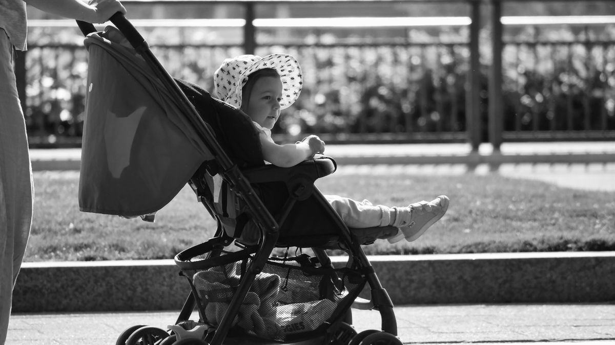 Adorable baby in a sun hat enjoys a stroll in a stroller, black and white urban setting.