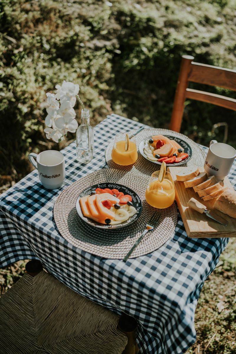 Vibrant al fresco breakfast setup with fruits, bread, and juice on a sunny day.