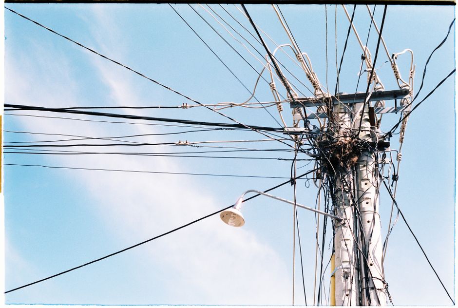 An intricate network of power lines and a lamp post against a clear blue sky.