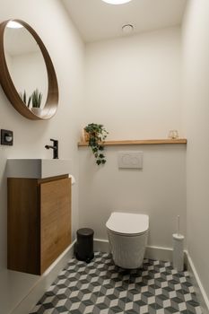 Stylish modern bathroom featuring a wooden vanity, geometric tiles, and round mirror.