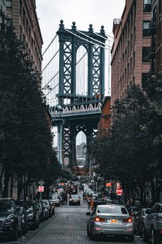 Iconic view of the Manhattan Bridge framed by city buildings in Brooklyn, NY.