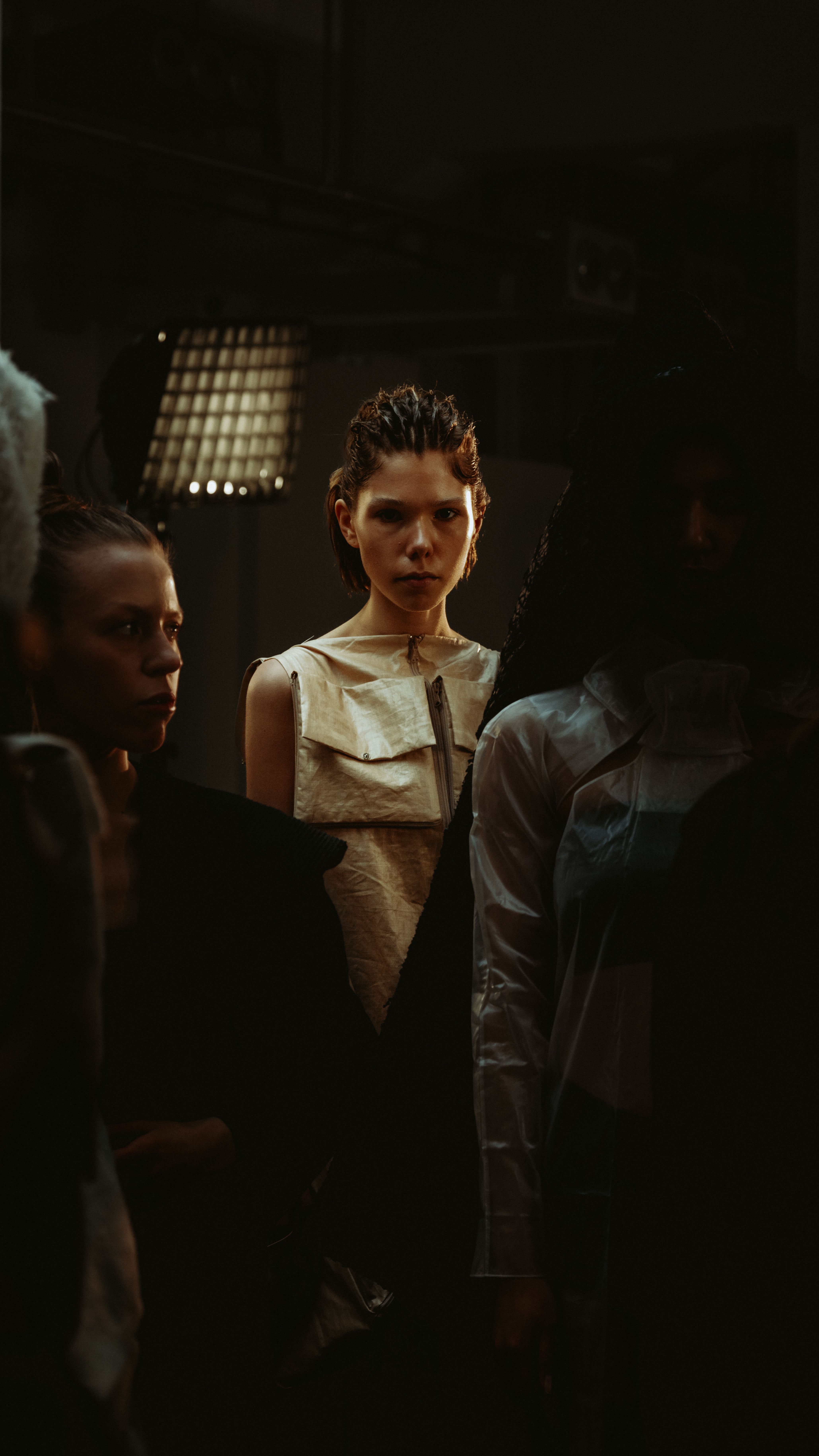 Model seated under bright backstage LED lighting during hair and makeup prep