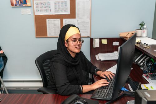 Free Young businesswoman in hijab working diligently at her desk in a professional office setting. Stock Photo