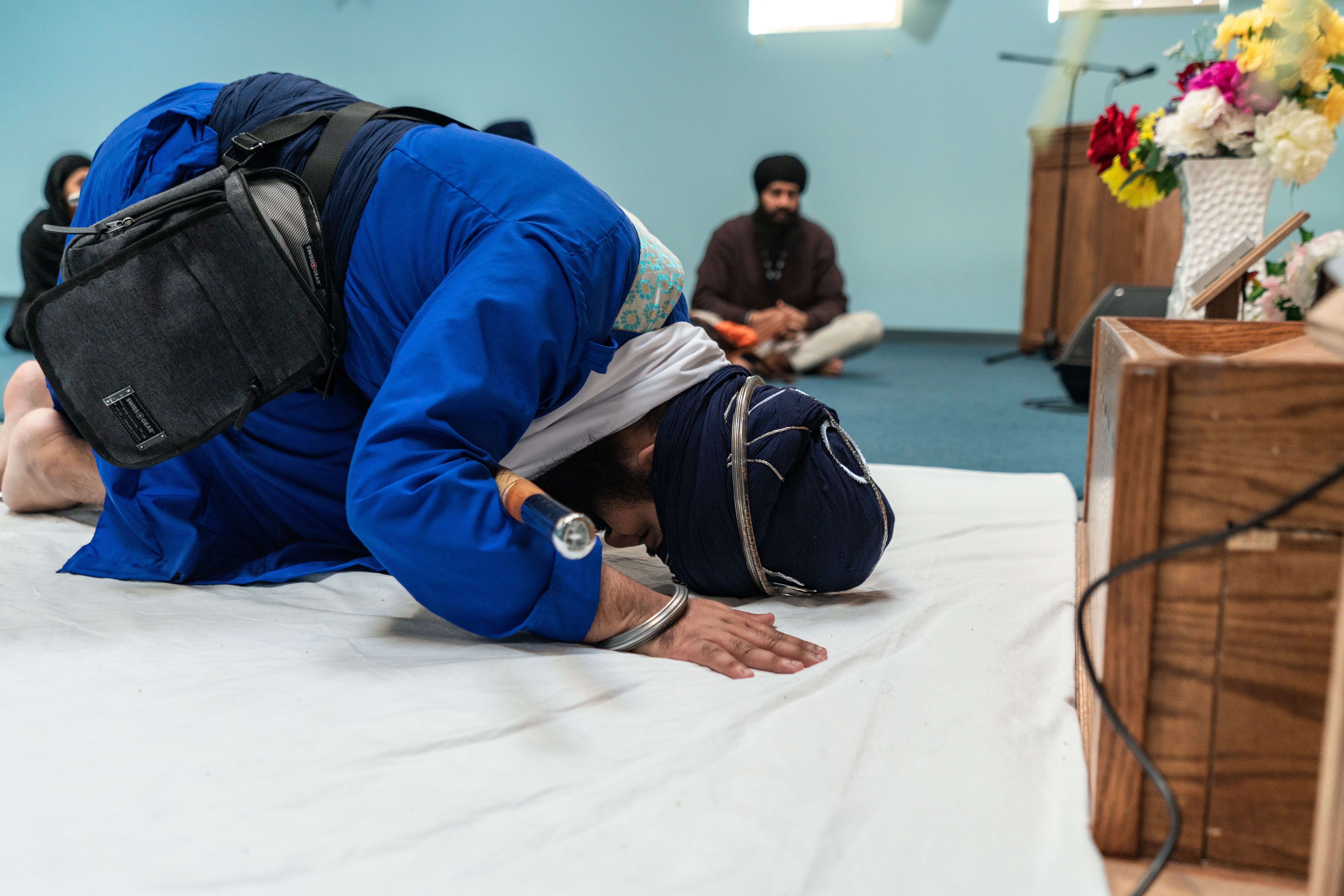 A Sikh man prostrating in prayer inside a gurdwara, emphasizing devotion and spirituality.