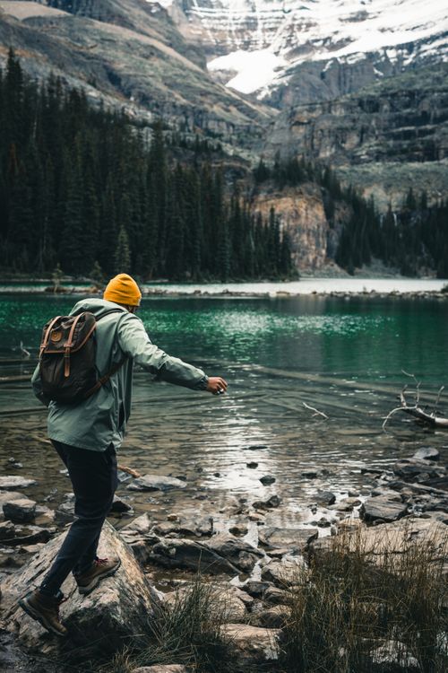 Free A lone adventurer hikes by remote mountain lake in Field, BC, Canada, surrounded by stunning scenery. Stock Photo