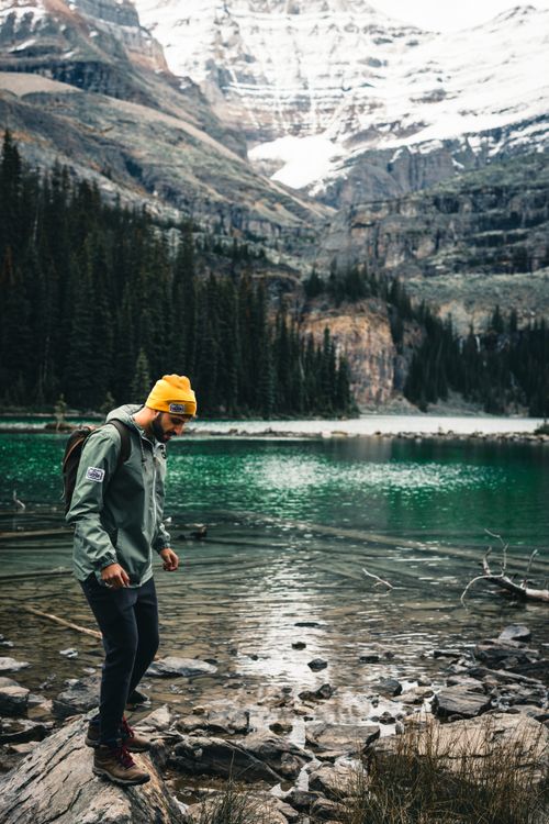 Free A hiker in a yellow beanie explores the serene Emerald Lake in Field, BC, surrounded by majestic mountains. Stock Photo