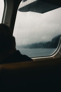 Dramatic view through a rainy ferry window overlooking misty waters in Gibsons, British Columbia.