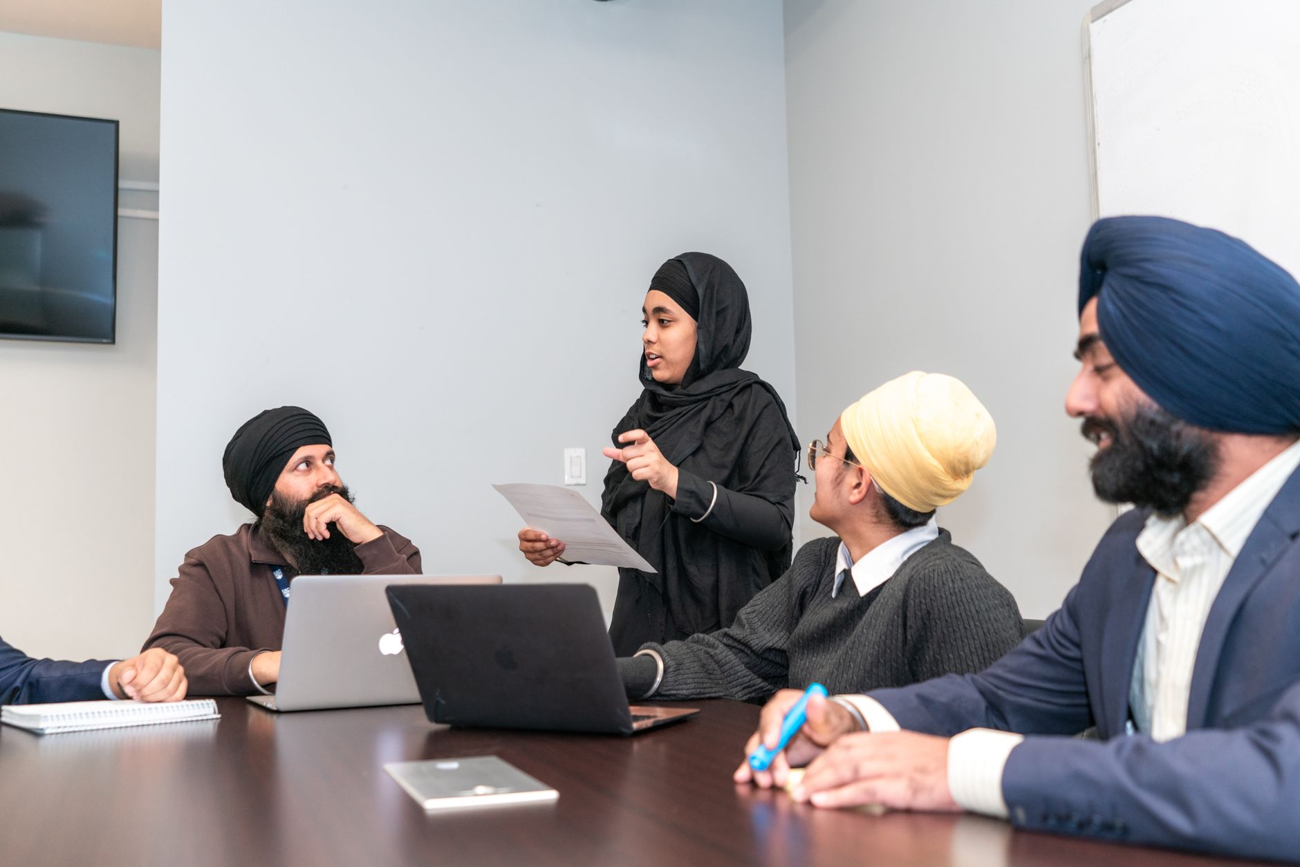 Multicultural team engaged in a business meeting discussing strategies around a conference table.