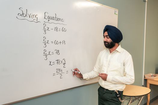 Teacher Solving a Mathematical Formula on a Whiteboard