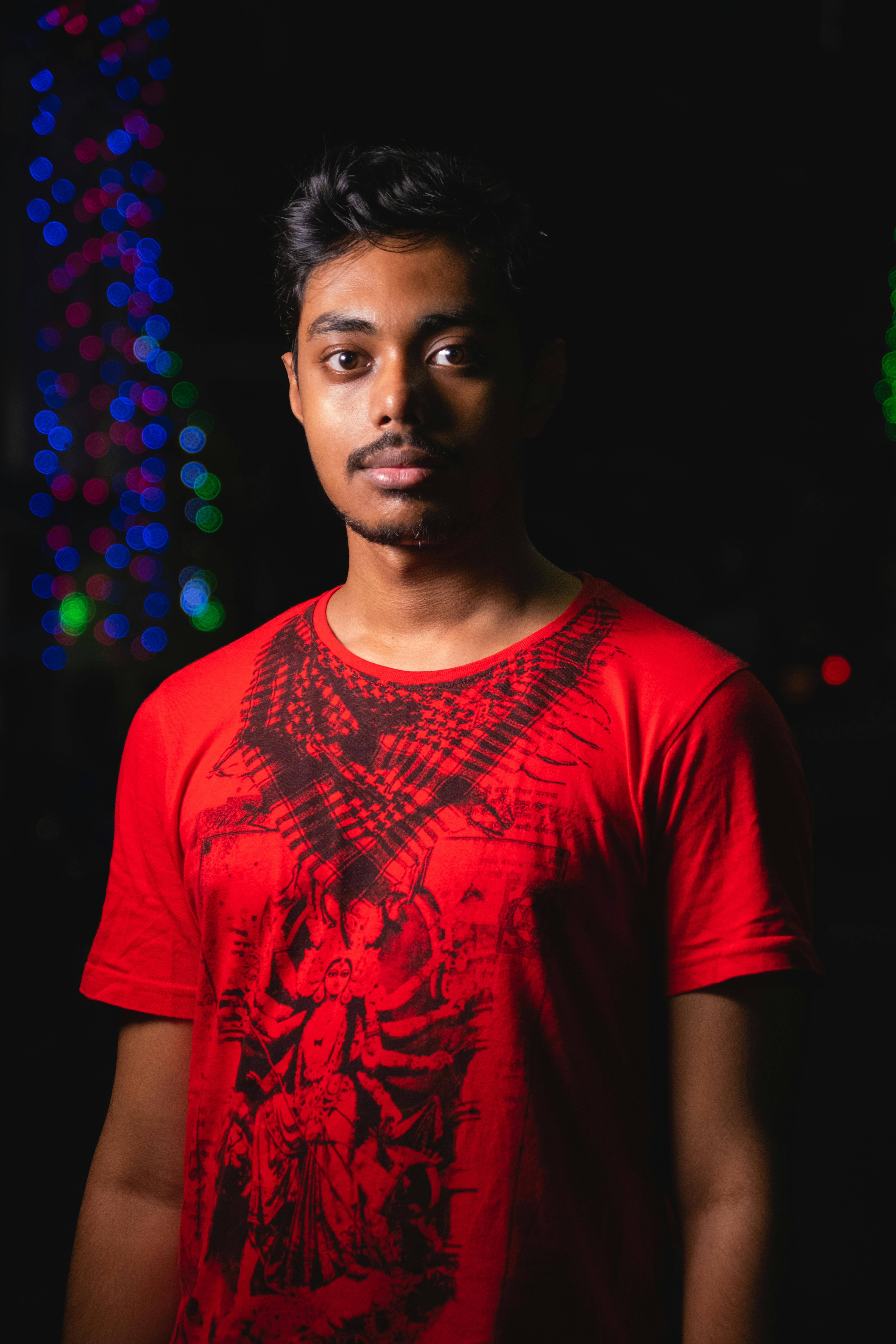 Captivating portrait of a young man in a red t-shirt against a night backdrop.