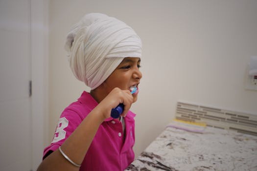 Young child in a turban practicing good dental hygiene by brushing teeth indoors.