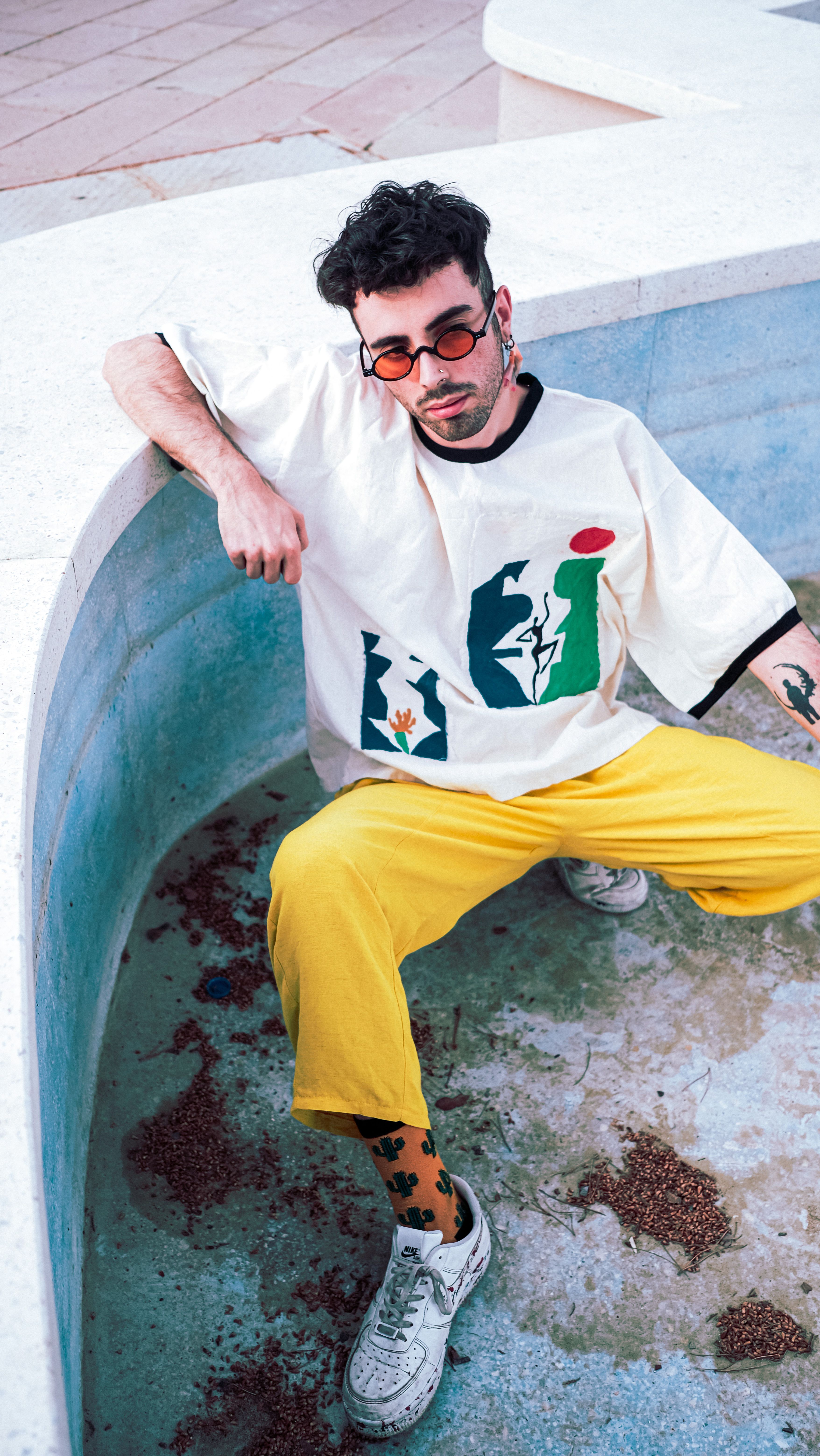 Trendy man with sunglasses and yellow pants posing in urban environment.