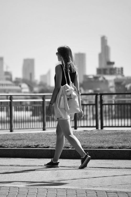 Free Black and white street photo of a woman walking in a modern cityscape. Stock Photo
