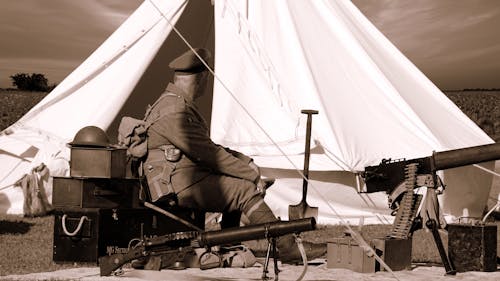 銃と白いガゼボの近くに座っている軍服を着た男のセピア写真