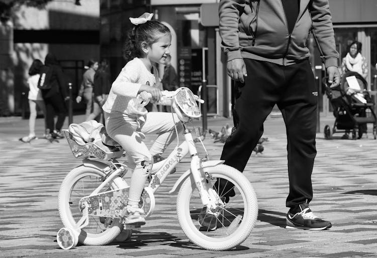 Girl Riding Bike Under Care Of Man