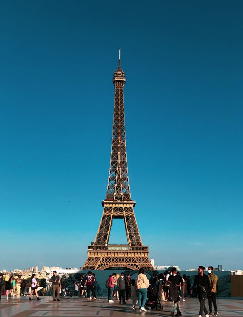 Free Stunning view of the Eiffel Tower in Paris with tourists gathered below on a sunny day. Stock Photo