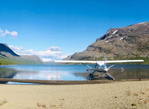 Free A seaplane rests by a tranquil mountain lake with a clear blue sky, perfect for travel and adventure. Stock Photo