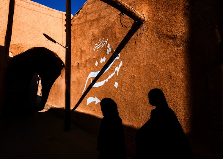 People Silhouette Under Writing On Wall