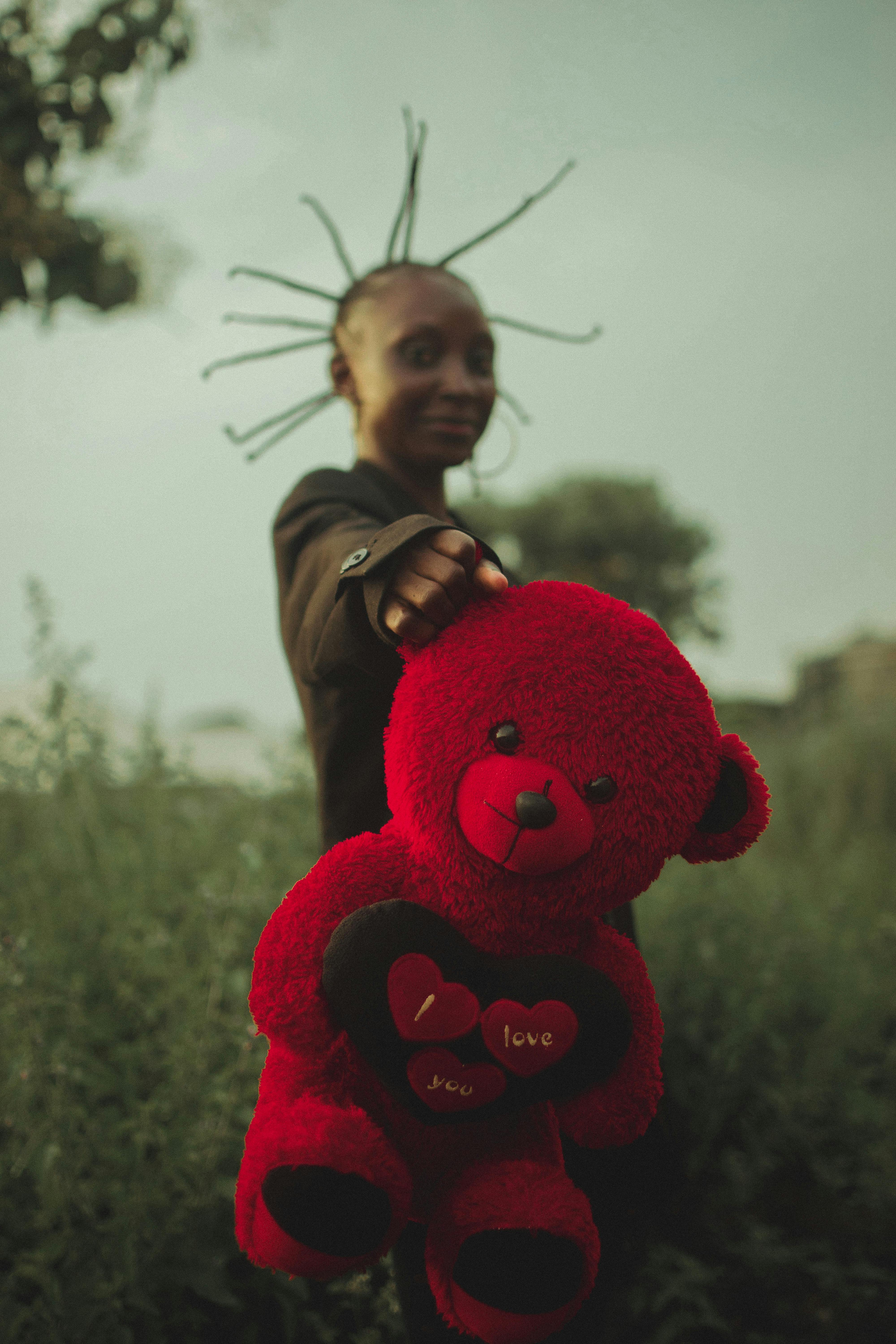 woman standing and holding red teddy bear