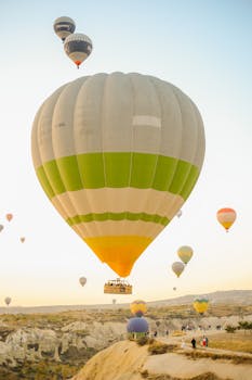 Vibrant hot air balloons float over scenic Cappadocia's landscape at sunrise.