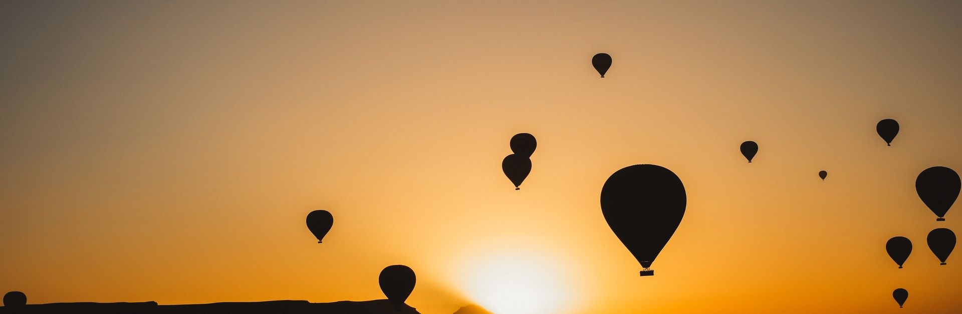 Silhouettes of hot air balloons floating in the sky against a vibrant sunset, symbolizing adventure