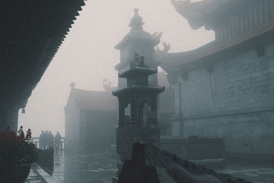 Yen Tu mountain spiritual landscape in Quang Ninh, stone pathways, ancient pagoda roofs in mist, pilgrims and cultural travelers, serene summer atmosphere, lush green forest, highly detailed