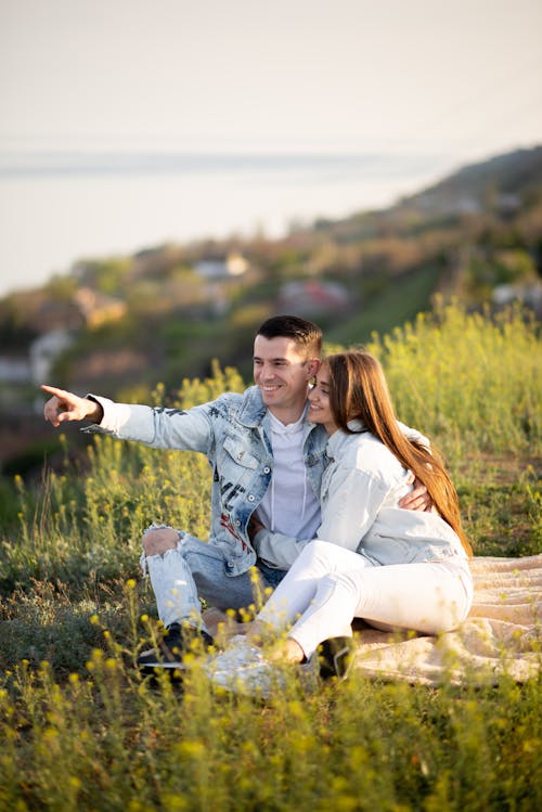 Smiling Couple Sitting Together on Meadow