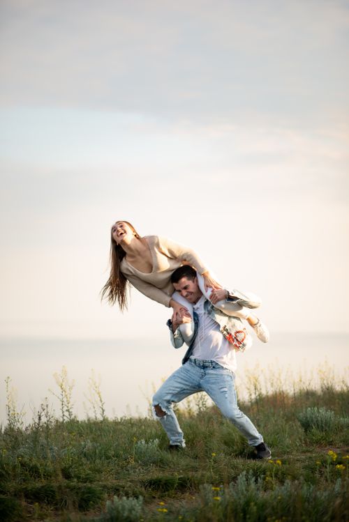 Free Happy couple enjoying playful moments in a grassy field. Stock Photo