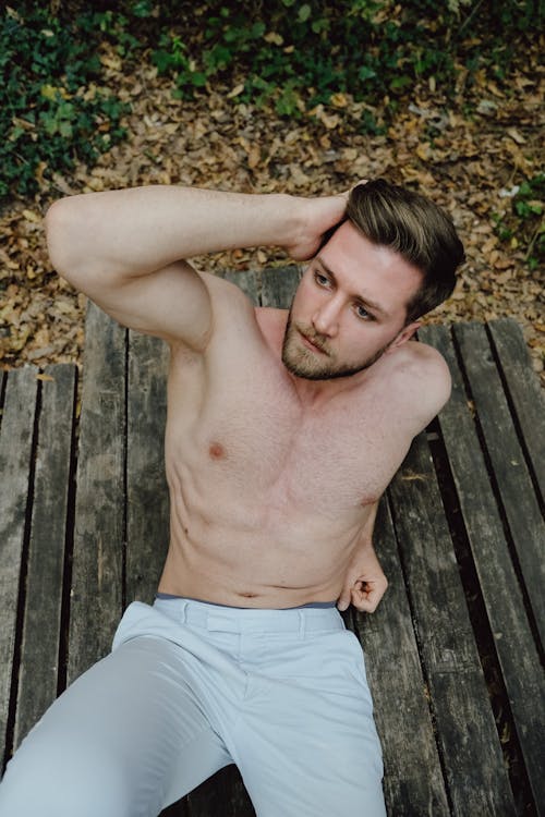 Portrait of a Shirtless Man Sitting on top of a Picnic Table