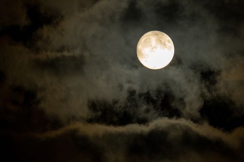Free A dramatic full moon surrounded by dark clouds in the night sky over Nelson, Wisconsin. Perfect for atmospheric mobile wallpapers. Stock Photo