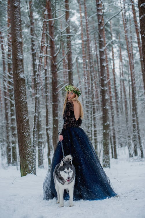Pretty girl with husky in forest at winter