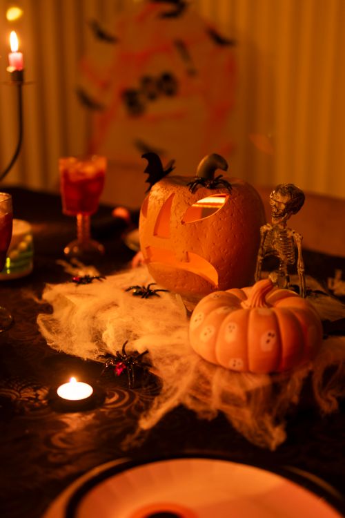 Free Atmospheric Halloween table setup with jack-o'-lanterns, skeletons, and candlelight. Stock Photo