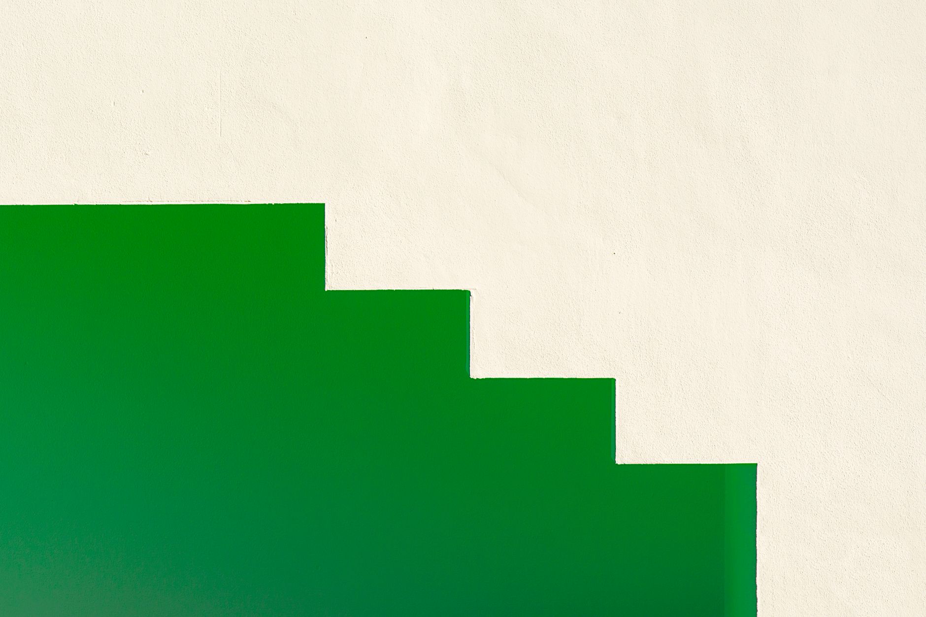 Minimalist design featuring a green staircase against a white wall, creating stark contrast.