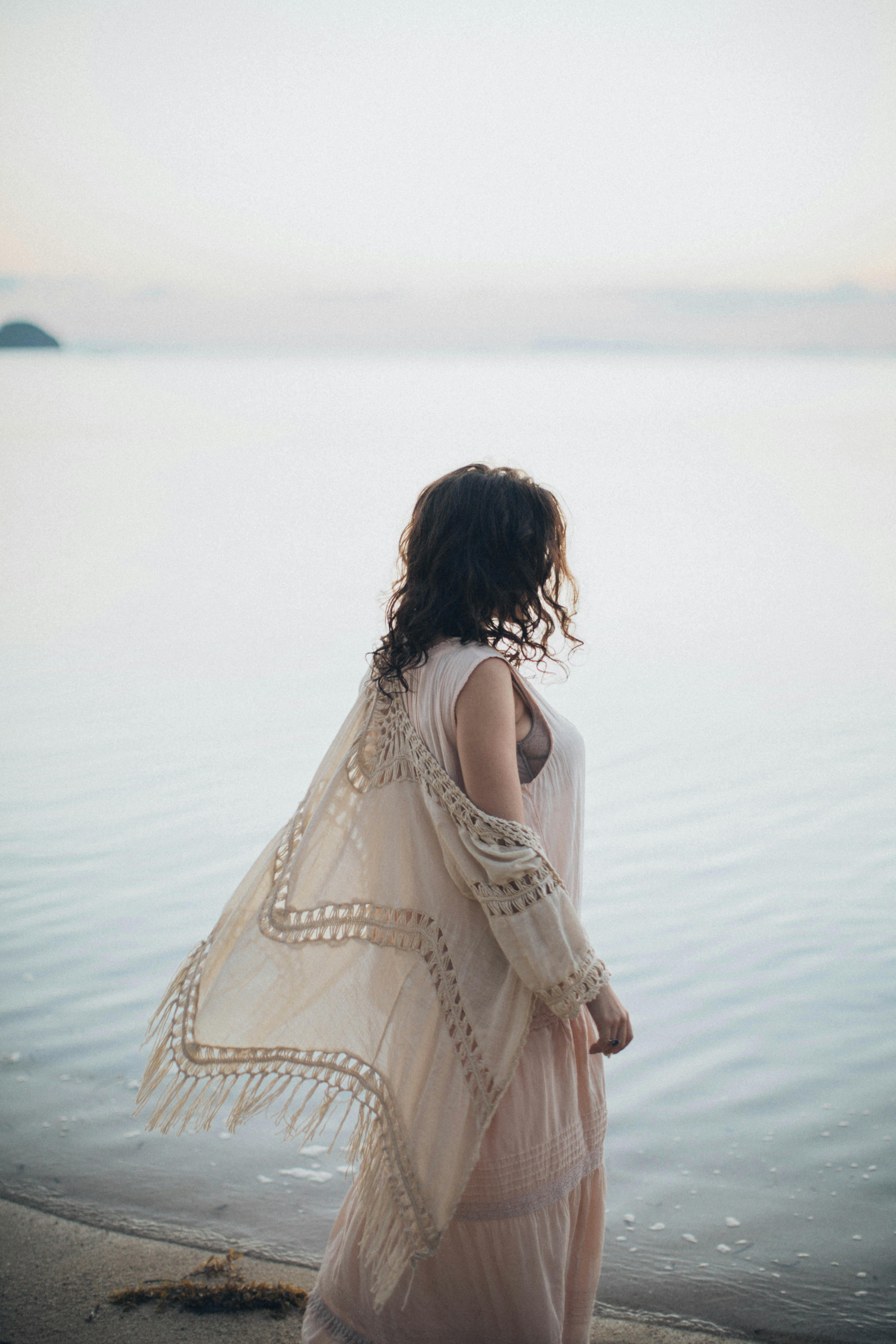一位身着飘逸连衣裙的女子凝视着宁静大海，这一刻被捕捉下来
