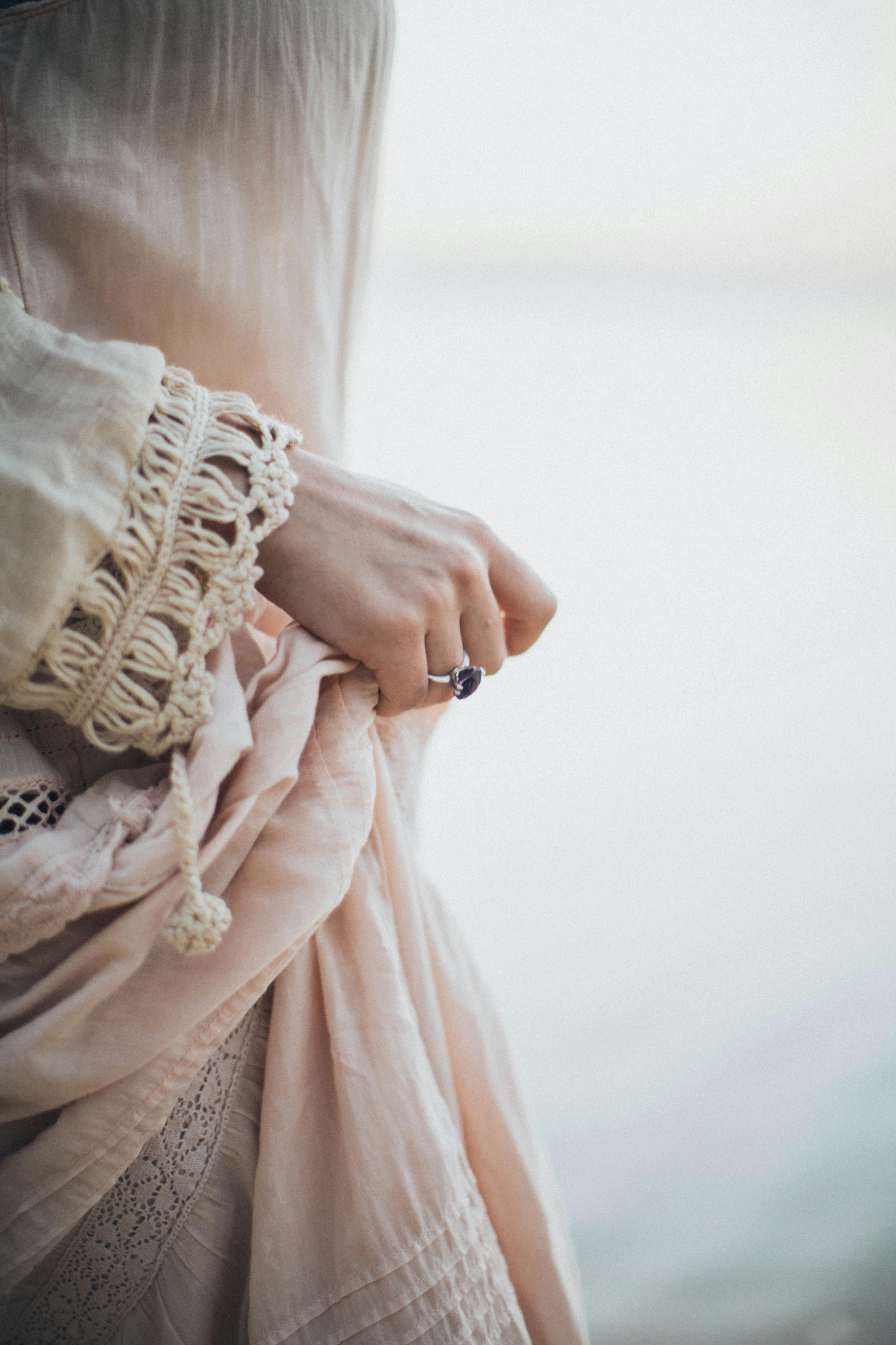 一只戴着戒指、披着蕾丝的女人的手，在宁静的背景中特写
