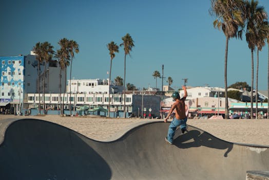 Skater performing tricks at a vibrant urban skatepark at Venice Beach with palm trees.