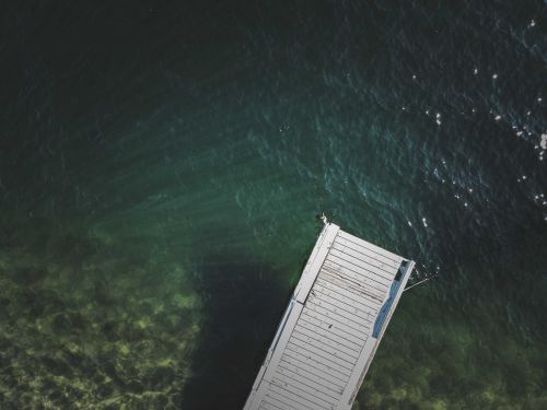 Free Top view of a wooden jetty extending into clear ocean waters, offering a tranquil scene. Stock Photo