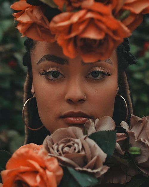 Free Close-up portrait of a woman surrounded by vibrant roses. Stock Photo