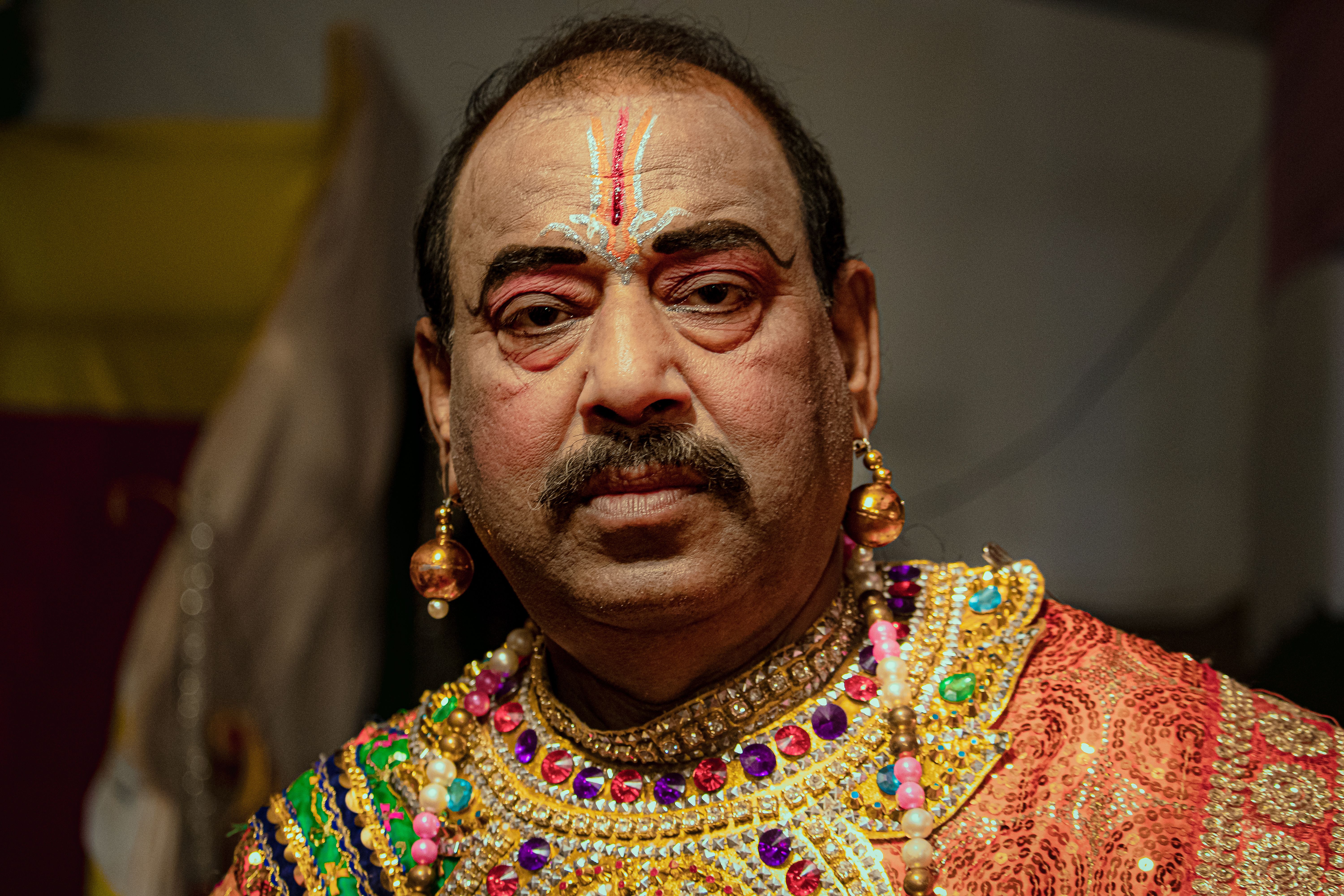 A senior man adorned in colorful traditional Indian clothing and jewelry