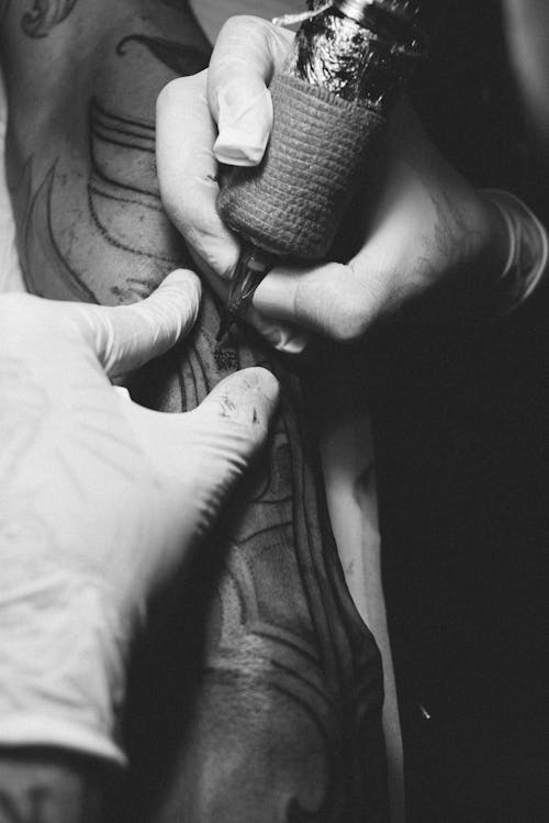 Black and White Photo of Hands Drawing a Tattoo
