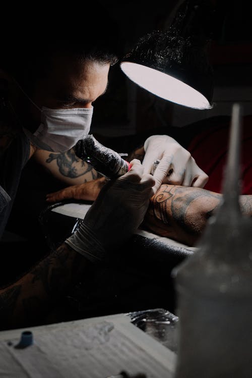 Tattooer Working in Mask