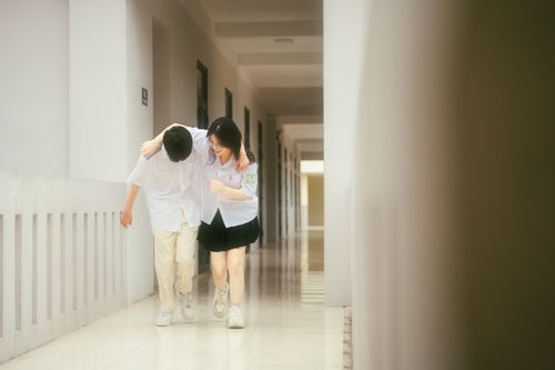 Free Joyful teenagers walking arm-in-arm, laughing in a school corridor. Stock Photo