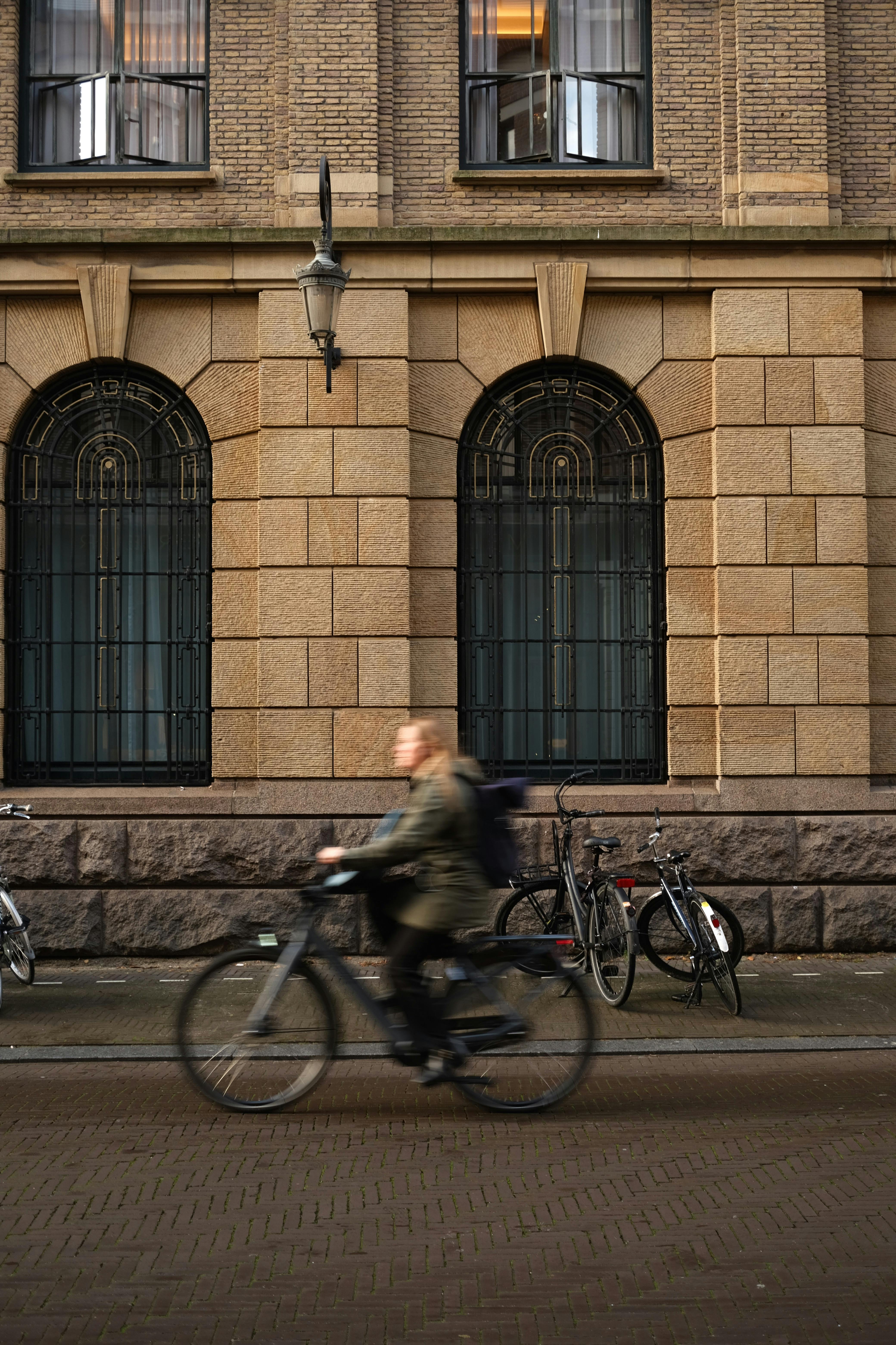 A person rides a bicycle past a historic building in The Hague, capturing the essence of urban cycling.