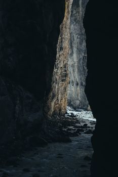 Explore the dark, rocky passage of Grindelwald's natural cave showcasing dramatic lighting and textures.