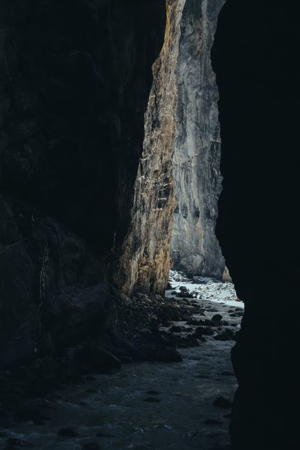 Explore the dark, rocky passage of Grindelwald's natural cave showcasing dramatic lighting and textures.