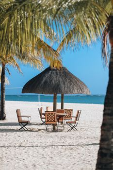 Serene beach setup under palm trees with chairs and umbrella on Mauritius coast.