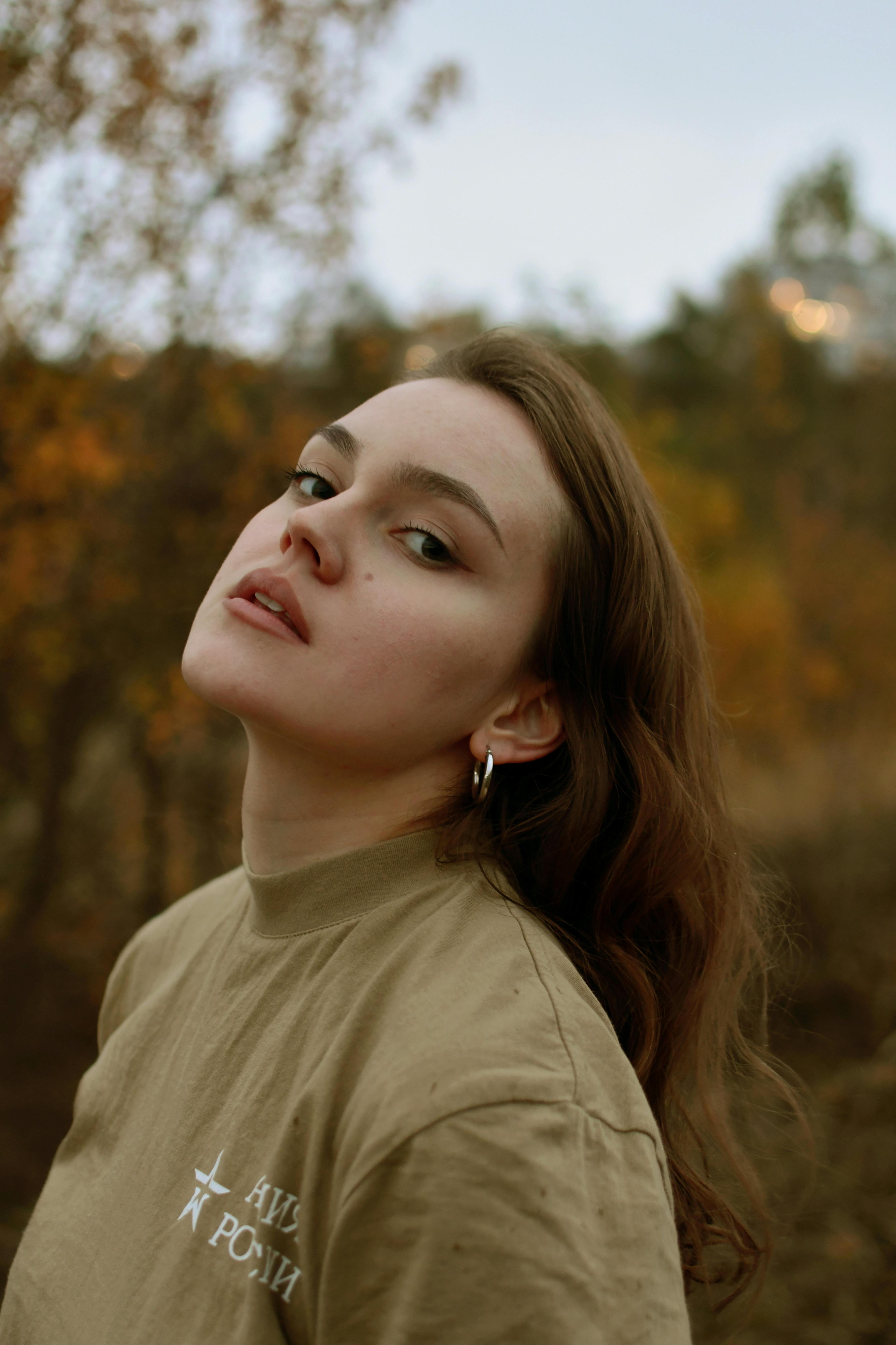 Elegant portrait of a woman with long hair in an autumn park setting.