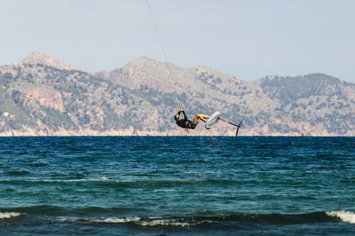Person Kitesurfing on Sea Shore