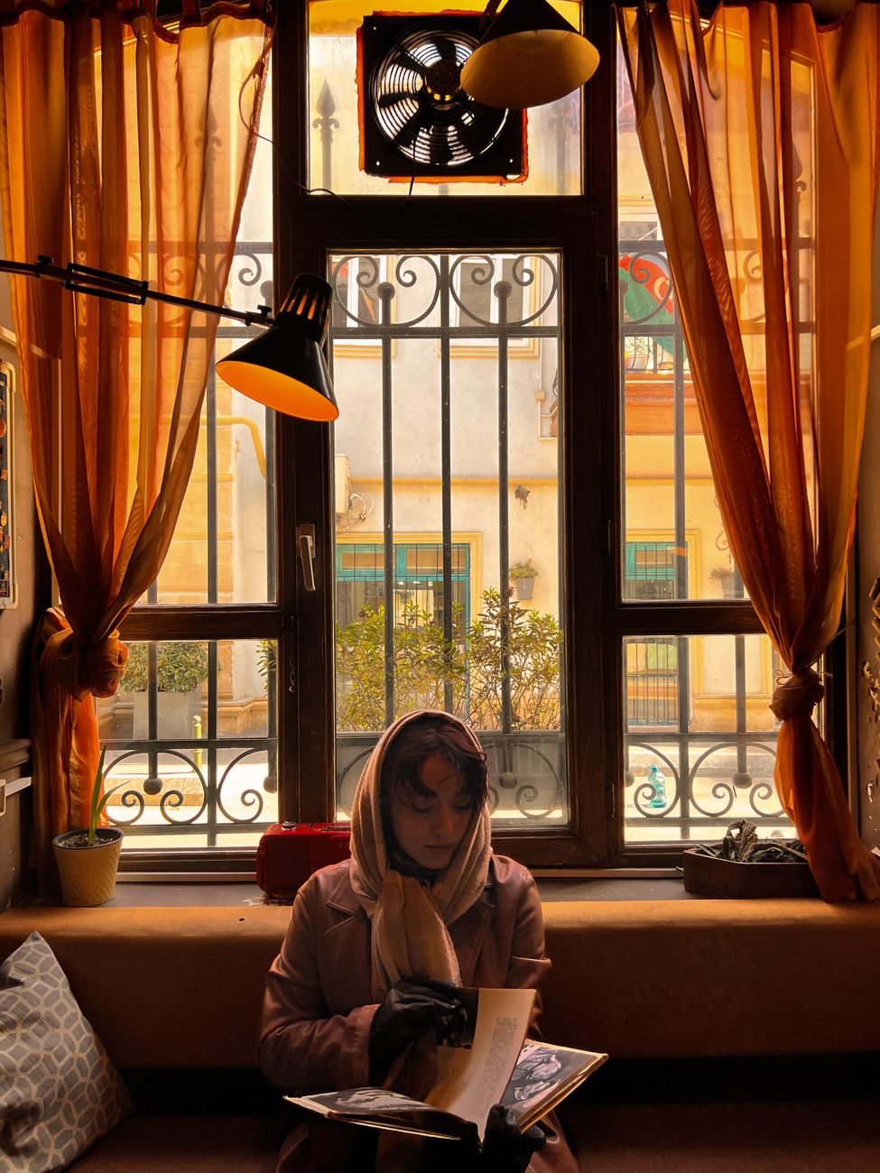 A woman in a hijab reads quietly by a sunlit window, creating a warm, serene atmosphere.. woman, hijab, reads